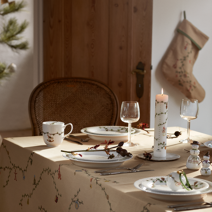 Dækket julebord med et kalenderlys og en julesok i baggrunden