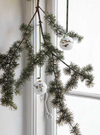 Julekugler på grangren i oplyst vindue