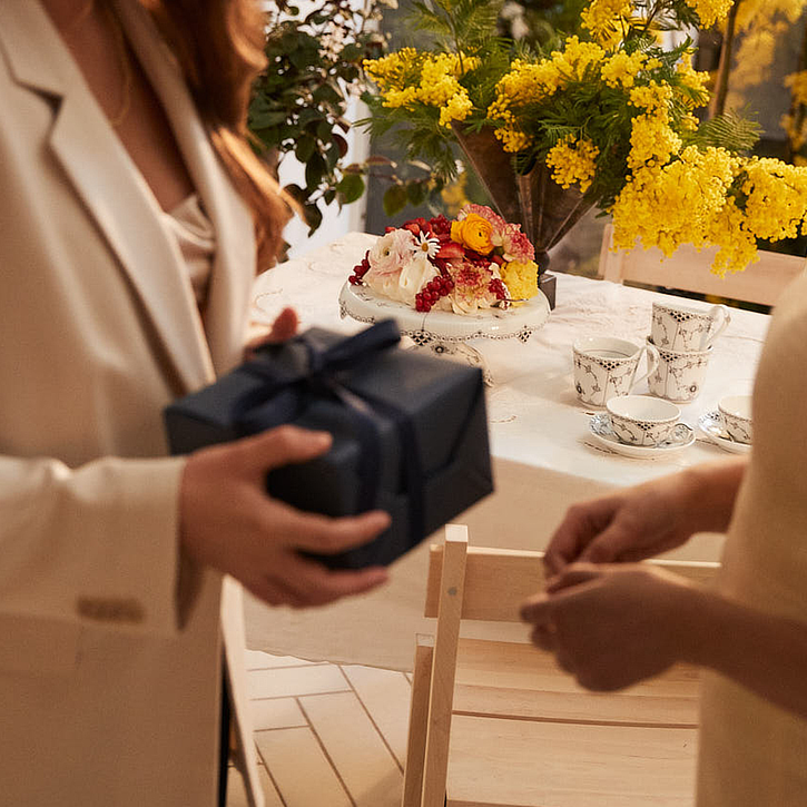 Firmagaver foran et bord med blomster